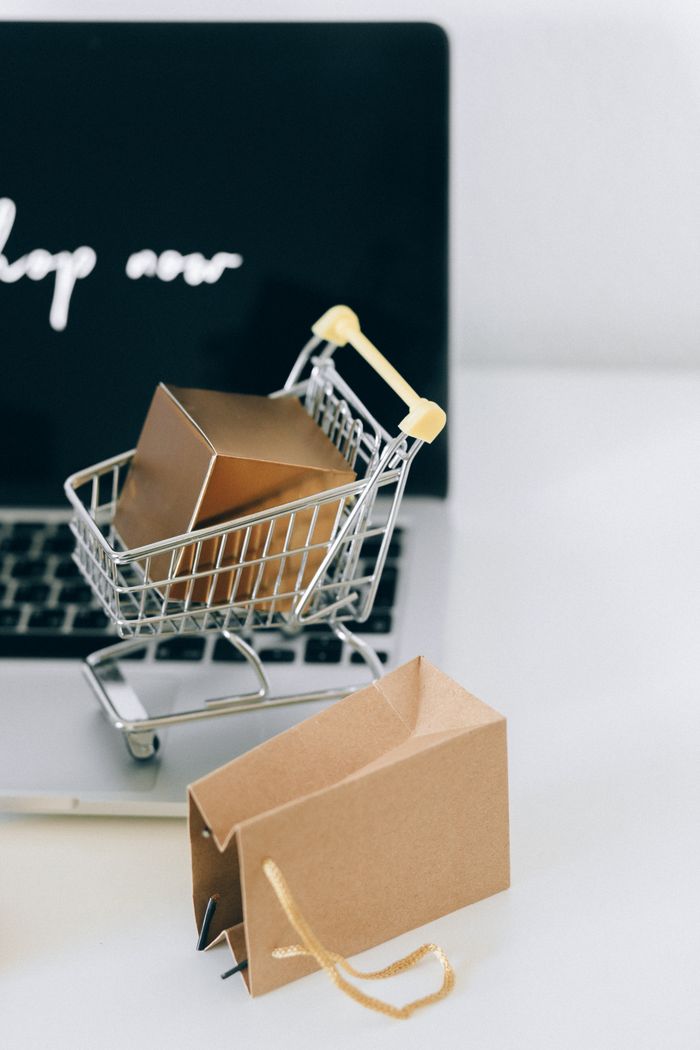 Mastering the First Impression: Your intriguing post title goes here A miniature shopping cart with a parcel on a laptop symbolizes online shopping and e-commerce.