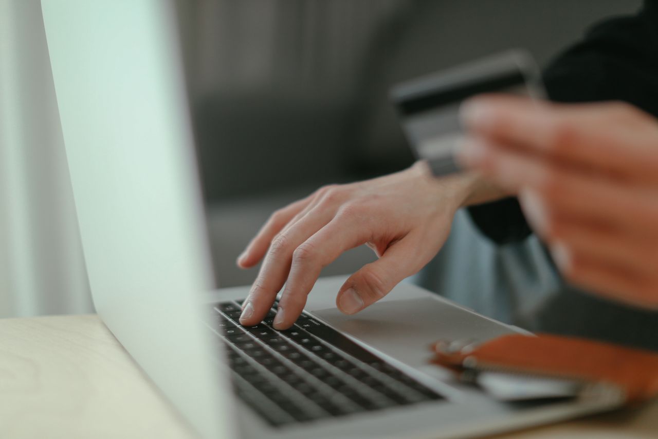 services-03 Close-up of hands holding a credit card and typing on a laptop keyboard for online shopping.
